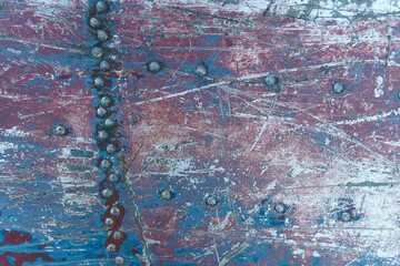 Texture of rusty metal with rivets, blue and red paints.