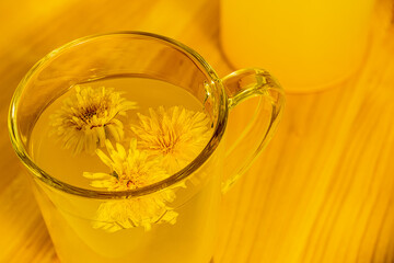 Dandelion tea in a glass cup on a uniform background, a natural product from Taraxacum protects against diseases, dandelion herbal tea improves cellular health, helps in weight loss