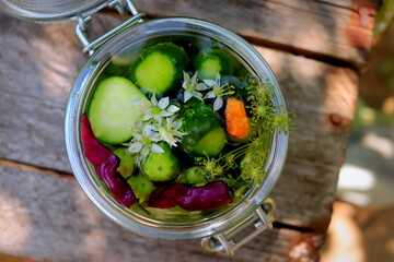 pickles in a jar with bitter pepper and inflorescence of wild garlic on a wooden surface selective...