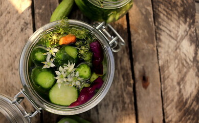 pickles in a jar with bitter pepper and inflorescence of wild garlic on a wooden surface selective focus, fermented vegetables