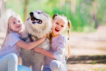 2 happy girls hugging a dog in the summer forest