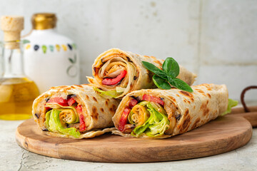 A wrap with a soft flatbread rolled around a filling with vegetables and cheese, tomato, fried...