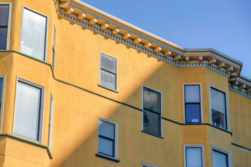 Fototapeta na wymiar View of a residential building with yellow stucco wall and decorative eaves in San Francisco, CA