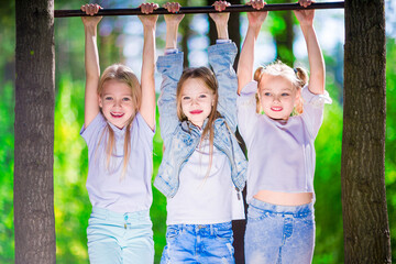 A group of 3 girls hanging on a horizontal bar in the forest. Fun and happiness