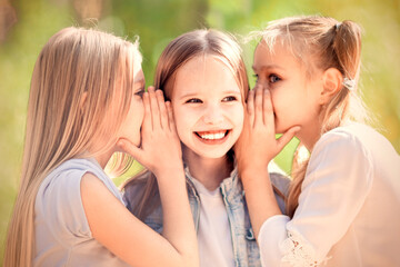 Three cheerful young girls are whispering for a walk in the park