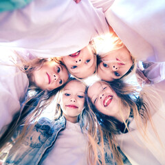 Happy joyful girlfriends standing together and forming a circle with their heads. Team spirit