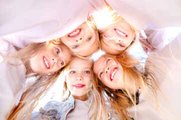 Happy joyful girlfriends standing together and forming a circle with their heads. Team spirit