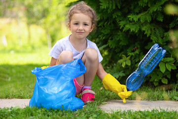 Girl collection plastic garbage in nature. kid picking up trash in park. Earth Day April 22. Save...