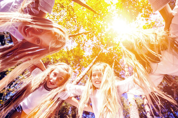 Fototapeta na wymiar A group of girls hugging themselves formed a circle, bent down, looking down. Walk in the summer forest. Bright sunny day
