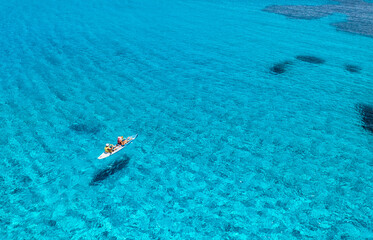Aerial view of kayak with people in blue sea at sunset in summer. Man and woman on floating canoe...