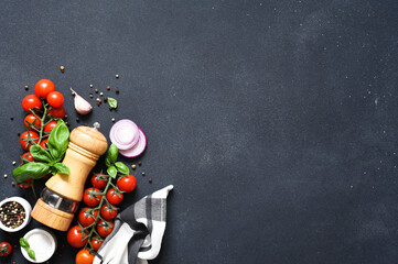 Pepper grinder, basil, spices and vegetables on a kitchen black table with space for text. Food...