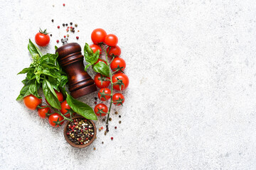 Pepper grinder, basil, cherry tomatoes on a white background with space for text. Food ingredients.
