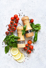Pepper grinder, basil, cherry tomatoes on a white background with space for text. Food ingredients.