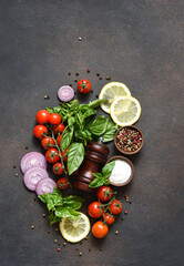Pepper grinder, basil, cherry tomatoes on a stone background with space for text. Food ingredients.