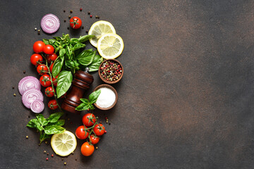 Pepper grinder, basil, cherry tomatoes on a stone background with space for text. Food ingredients.