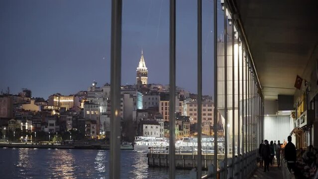 View through window on a coastal town lights and rippling water. Action. Southern city late in the evening.