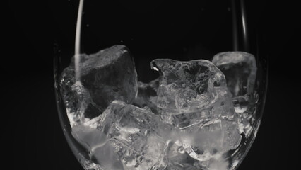 Ice cubes falling empty transparent glass closeup. Cocktails preparation concept