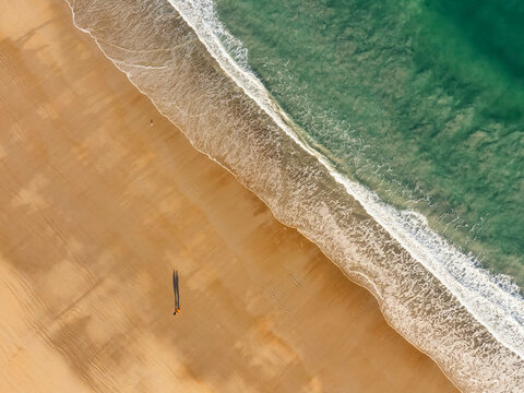 Drone picture of a couple walking on a french sandy beach in front of the ocean