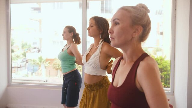 Three women having yoga classes in the studio - running their hands above the chest