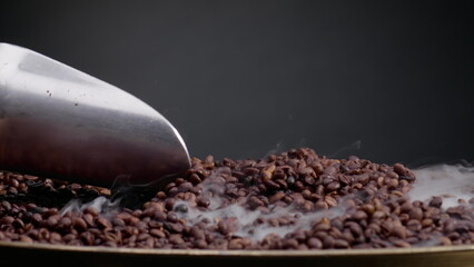 Process roasting coffee beans mixing shovel. Close up steam rising over seeds 