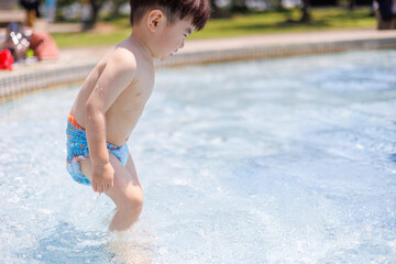 プールで水遊びをする男の子