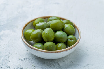 large green olives on bowl on white concrete table