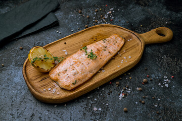 Salmon steak on the grill on board on dark stone table