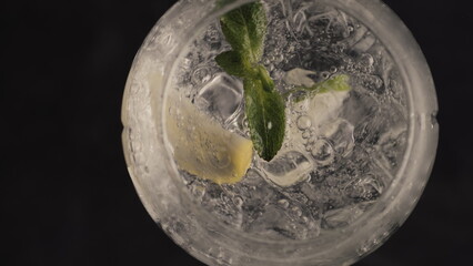 Bubbled lemon ice mint cocktail spinning glass closeup. Summer drinks concept