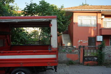 Roter Lastwagen mit Pritsche und Plane vor einem Wohnhaus im Sommer bei Sonnenschein in Adapazari...