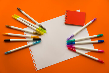 Creative kids, concept. Colorful crayon paints and blank notepad on orange color background markers, red little notepad. Empty paper for painting, space, template. Education, Back to School concept.