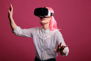 Portrait of one person with pink hair playing with vr goggles, using 3d interactive simulation...