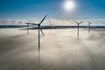 onshore wind turbine standing in fog in the morning sun