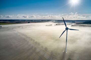 onshore wind turbine standing in fog in the morning sun
