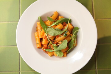 Italian pasta rigatoni close up top view with arugula and red sauce