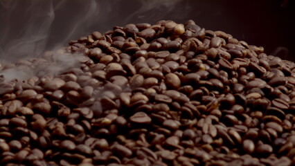 Closeup steam rising over coffee seeds in slow motion. Roasting caffeine grains.