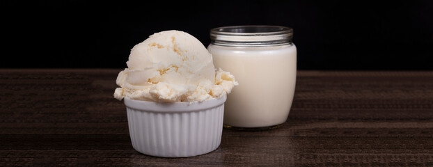 Tasty White cream flavored ice cream. Served in a white pot with a glass of powdered milk in the background.Photography with space for text and edits on the sides.