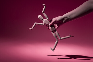 broken wooden doll in a human hand on a colored background