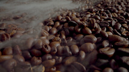 Steam coming coffee beans close up. Aromatic seeds roasting in super slow motion