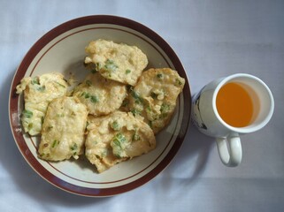 fried tempeh on a plate and a glass of orange drink