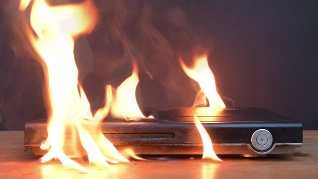 The DVD player sparks and burns on the table, a fire breaks out, an electrical wiring flame ignites, a fire in the apartment due to faulty household appliances.