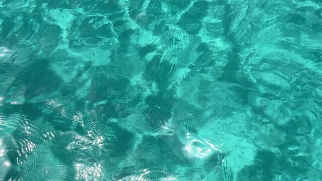 turquoise water texture on a beach with crystal clear water and white sand, light waves with sun reflections on a summer day, turquoise blue water undulations, resolution 4k