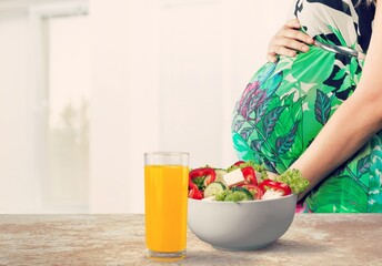 Pregnant woman with fresh salad in bowl. Healthy lunch concept.