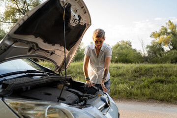 Fototapeta na wymiar one mature woman stand by car with broken failed engine on the road
