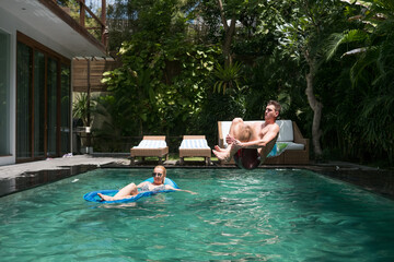 Young guy dive bombing his girlfriend in the pool