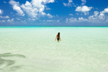 Woman walking out into the tropical ocean on vacation