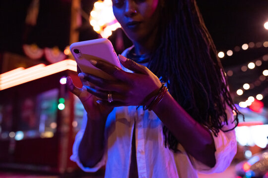 Black woman scrolling news on cellphone at night