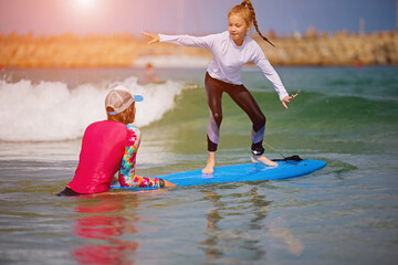 Surfing with surf board. Instructor teaches the school girl to swim with a sup board