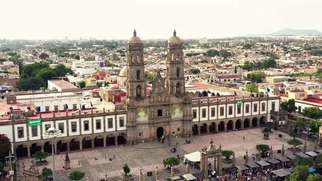 Vuelo drone sobre plaza de las americas con la basilica de zapopan de fondo templo iglesia convento con turistas desconocidos pasando caminando  sobre explanada