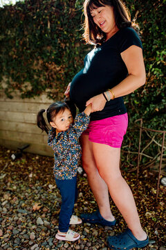 Pregnant Asian mom outdoors with daughter