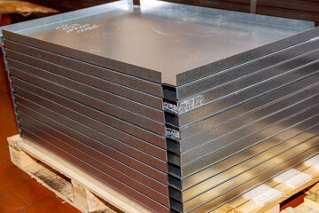 Sheet metal bending on a hydraulic machine at the factory. A stack of bent thin sheet metal products on a pallet.